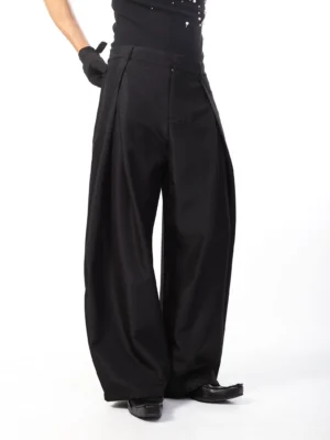 Black pleated balloon trousers front view worn with black top and leather shoes in minimalist studio