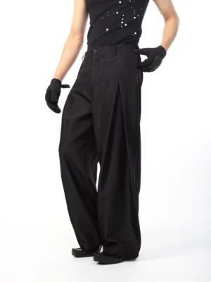 Black sculpted wide-leg balloon trousers three-quarter side view showing deep pleats and draped silhouette