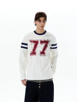 Front half-body view of off-white 77 varsity graphic long sleeve streetwear tee with navy sleeve stripes and distressed red chest print