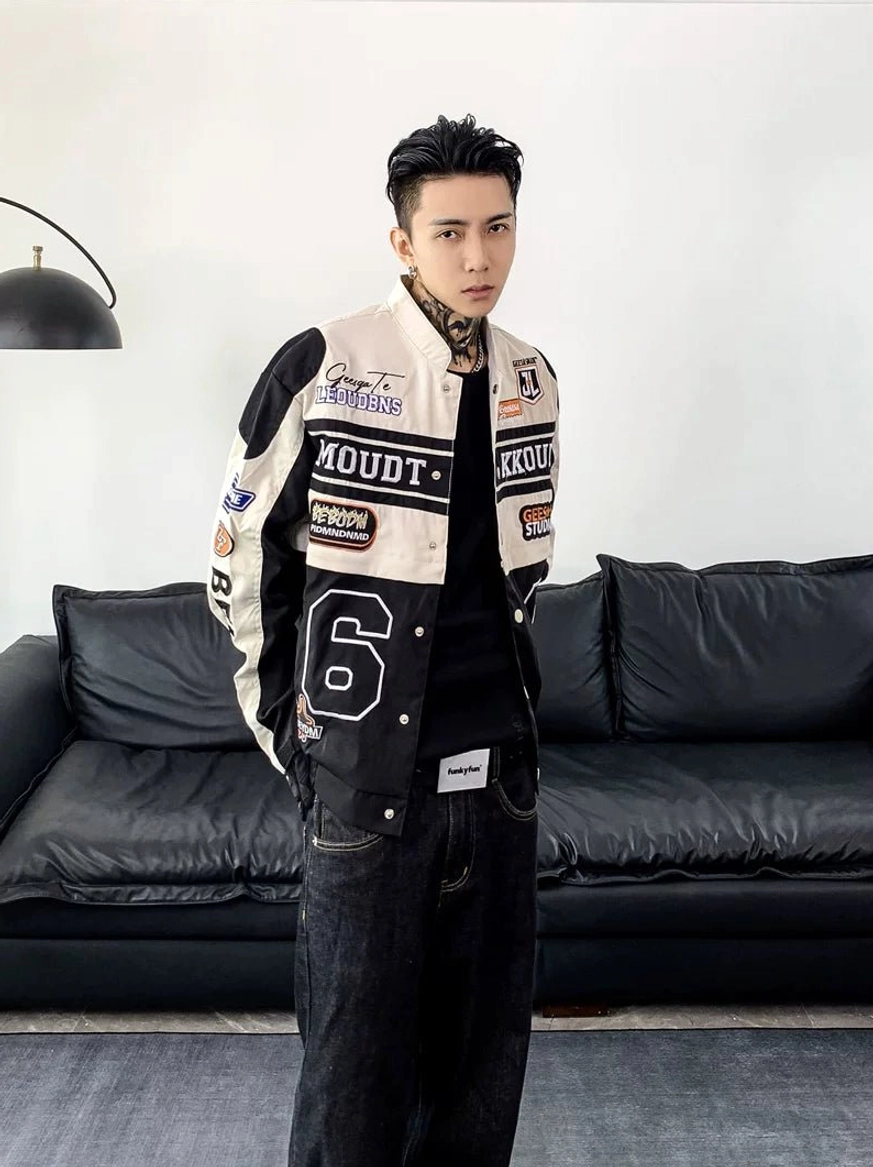 Three-quarter view of an off-white and black motorcycle varsity jacket with racing patches, snap front, and structured streetwear fit