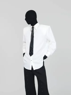 Off-white oversized dress shirt with crystal studded collar and black chain tie styled with wide-leg trousers