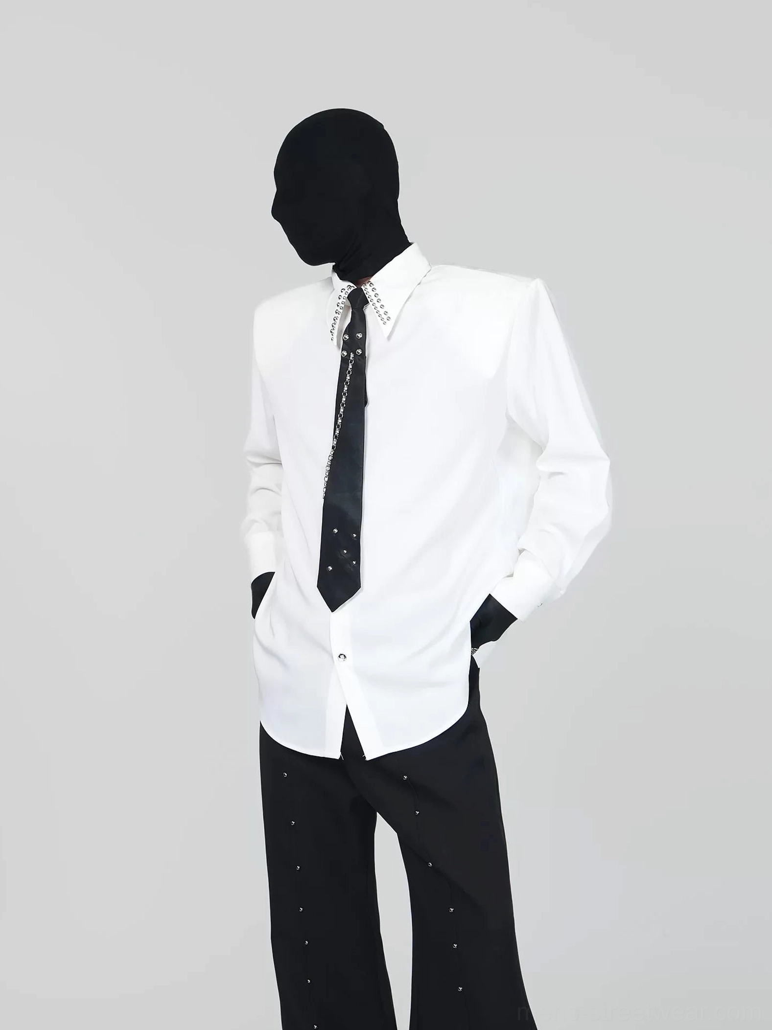 Off-white oversized dress shirt with crystal studded collar and black chain tie styled with wide-leg trousers