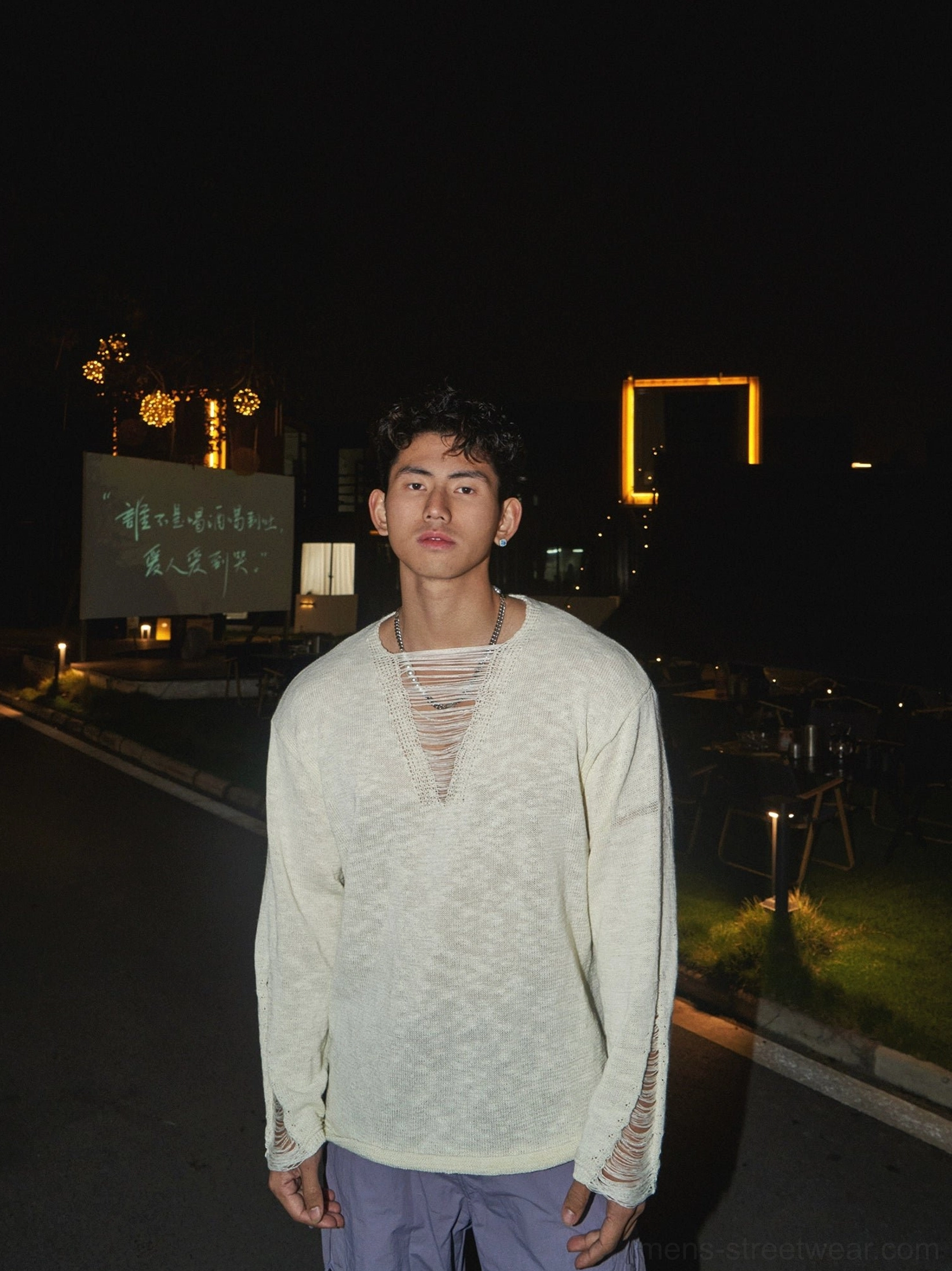 Close-up of off-white distressed lace-up V-neck knit shirt showing frayed collar and sleeve cuff details