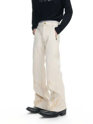 Off-white flare embroidered trousers shown in a front three-quarter full-body view with golden flame embroidery at the cuffs, high-waisted silhouette, side zipper detail, black top, and leather shoes