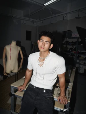 Off-White lace-up ribbed slim-fit T-shirt with crisscross V-neck styled with black cargo jeans and layered necklaces in an industrial streetwear studio