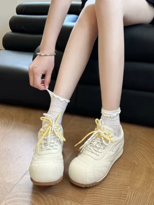 Off-white low-profile streetwear sneakers worn with frilled ankle socks in a relaxed indoor Korean fashion outfit