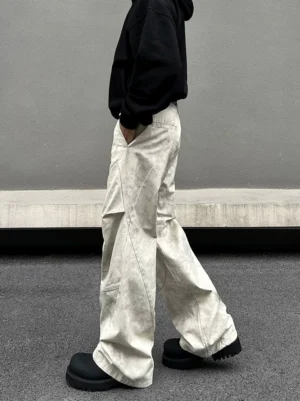 Side profile of relaxed off white marble wash cargo pants with oversized wide leg fit and curved seam detailing styled with a black hoodie