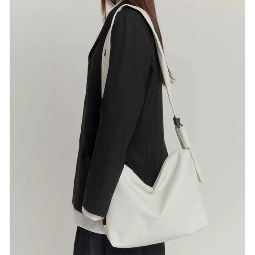 Off-white minimalist PU leather tech sling bag side view worn with black blazer in Seoul fashion styling