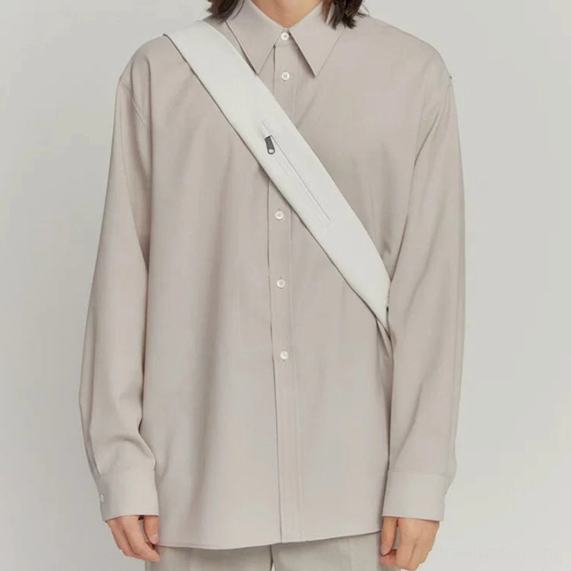 Off-white minimalist PU leather tech sling bag worn crossbody with wide padded strap and zipper pocket