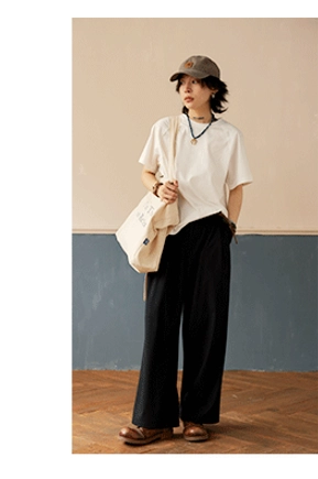 Off-white minimalist cotton raglan crew neck T-shirt paired with black wide-leg pants and canvas tote