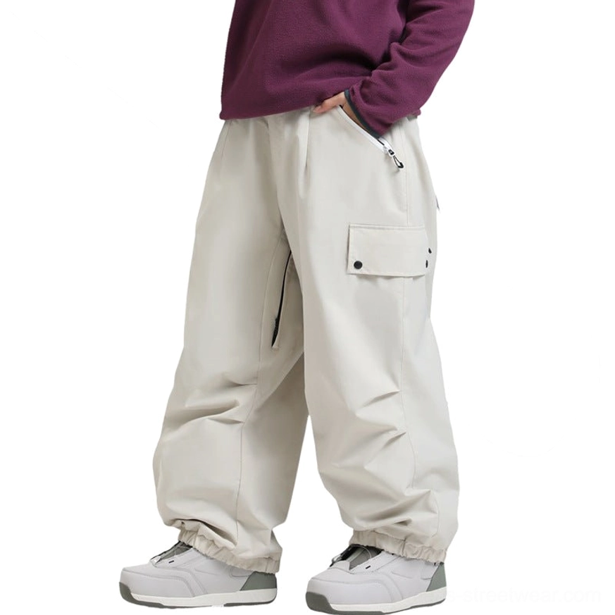 Off-white oversized cargo snow pants with relaxed wide-leg shape, thigh flap pocket, side zipper pocket, elasticated cuffs, and outdoor streetwear styling