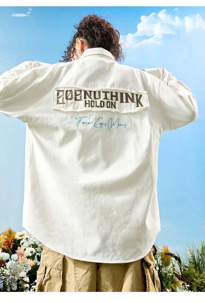Off-white oversized embroidered button-up shirt viewed from the back with full embroidered patch, curved hem, and relaxed sleeves