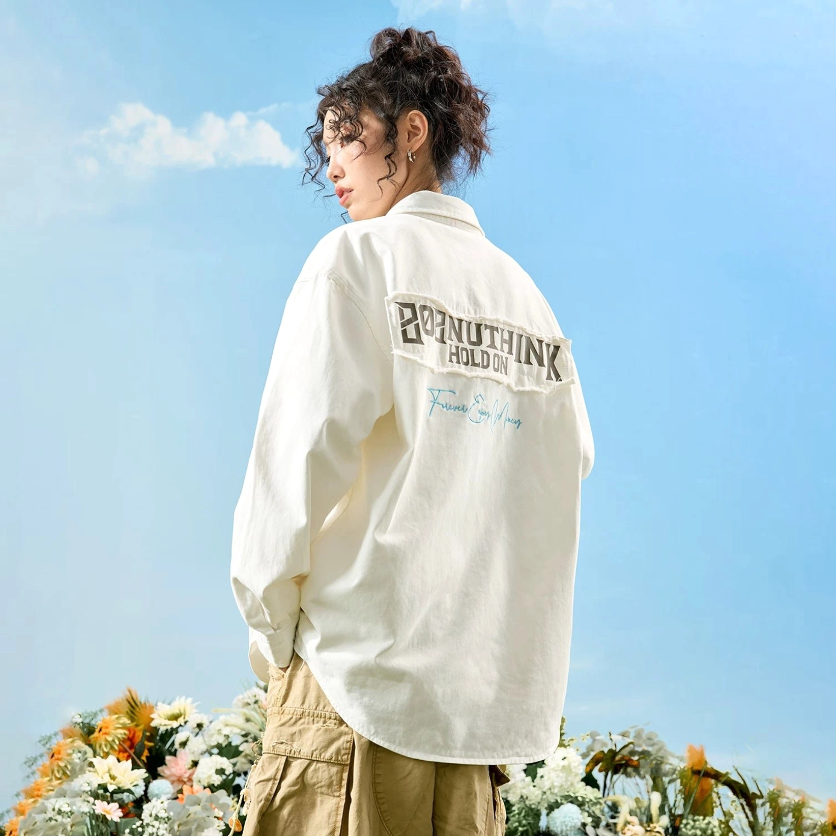 Female model wearing an off-white oversized embroidered button-up shirt with large back patch and tan cargo pants in casual street style