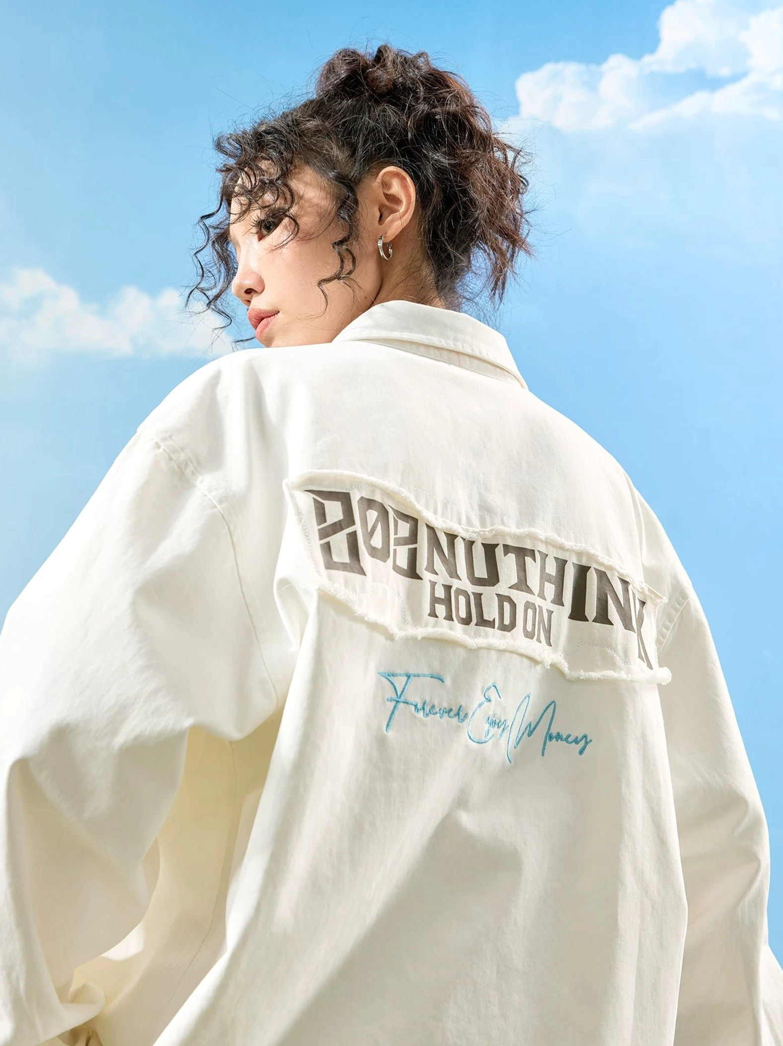 Off-white oversized embroidered button-up shirt on a female model showing the frayed back patch, loose sleeves, and handwritten slogan