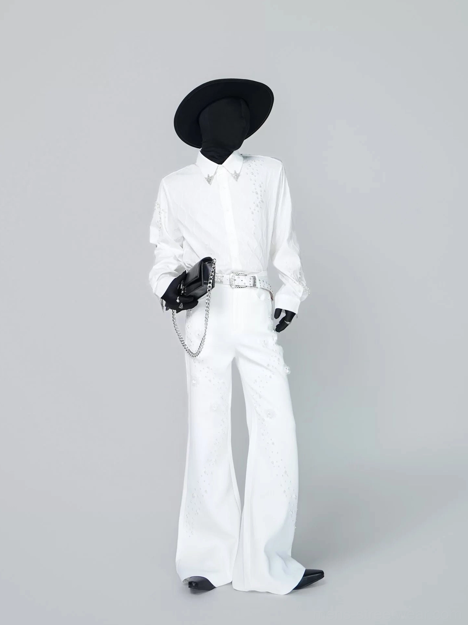 Full outfit view of off-white pearl embellished flare trousers styled with a tailored white shirt belt hat and chain handbag