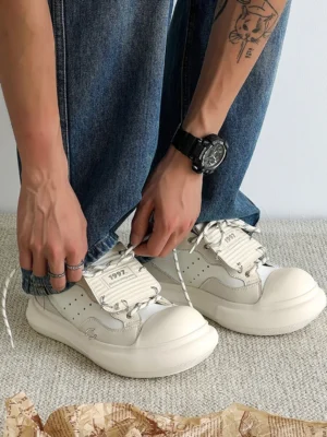 Close-up view of off-white chunky platform sneakers being tied with dual-tone laces and a decorative 1997 lace patch
