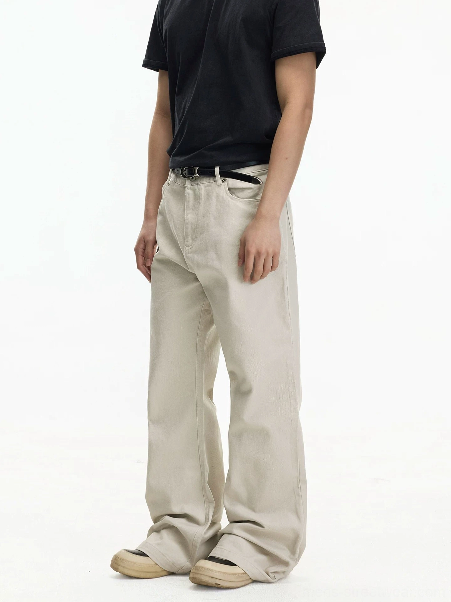 Side view of off-white relaxed wide leg jeans with long draped hem and clean denim silhouette