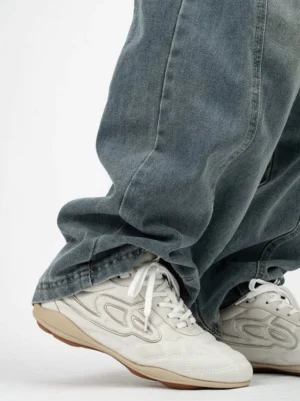 Off-white retro low-top sneakers with gum sole and white side graphic worn with loose washed blue jeans