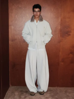 Full-length front view of an Asian male model wearing an off-white shearling collar bomber jacket with relaxed wide-leg trousers and brown loafers