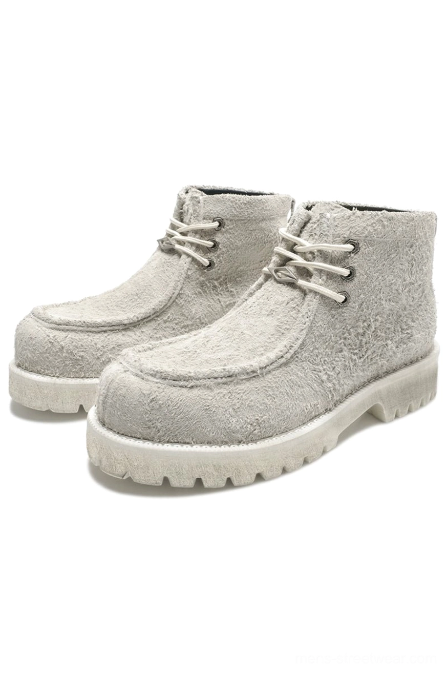 Off-white shearling moc toe lug boots with soft cowhide suede texture, round laces, and thick light rubber sole on white background