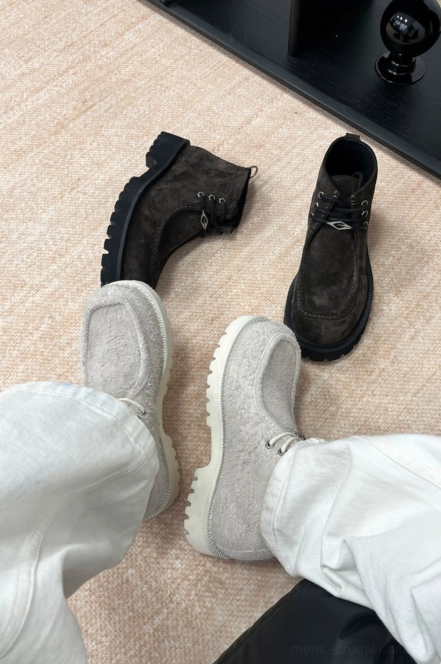 Off-white shearling moc toe lug boots styled on foot with light denim pants in a casual indoor streetwear setting