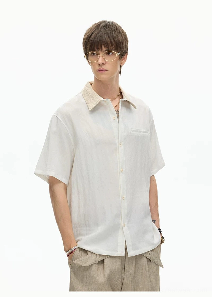 Off white short sleeve textured streetwear shirt with chest pocket and button front worn with beige trousers
