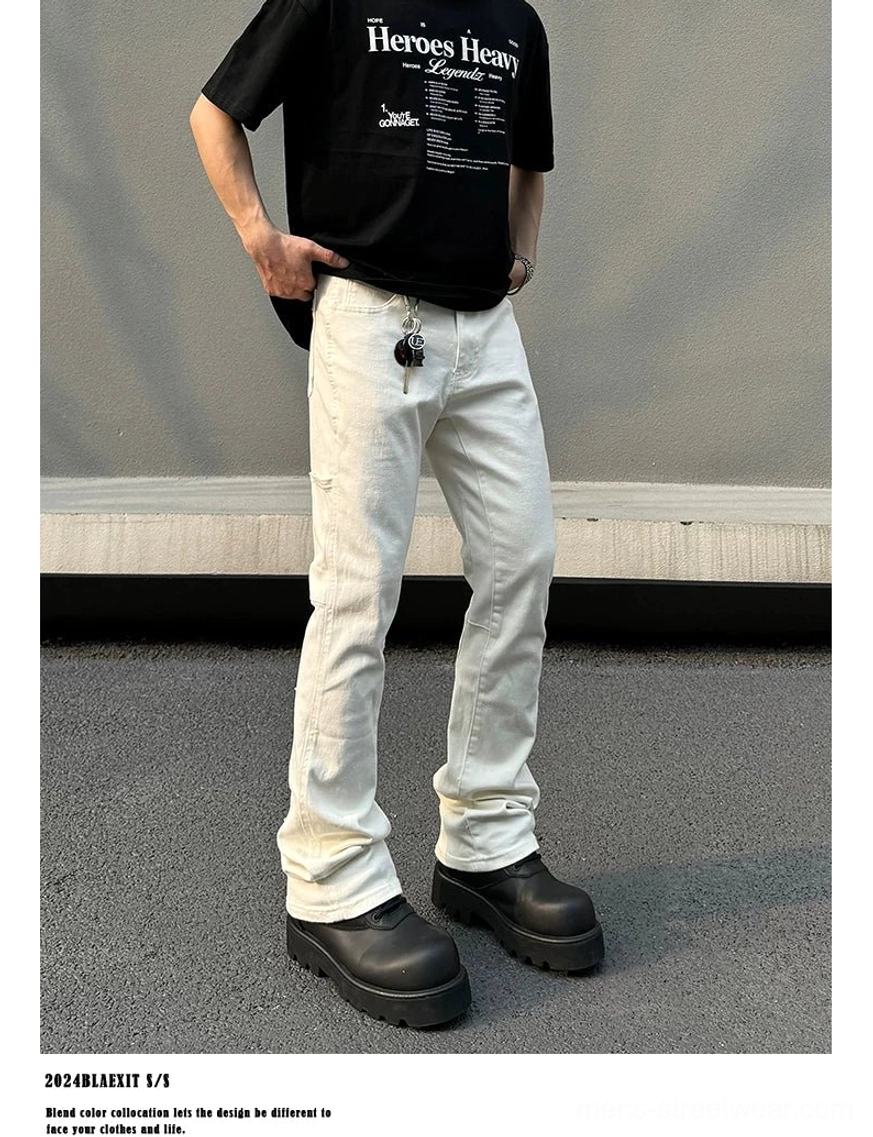 Three-quarter front view of men's off-white flare jeans with clean denim finish, metal waistband accessory, and platform boots