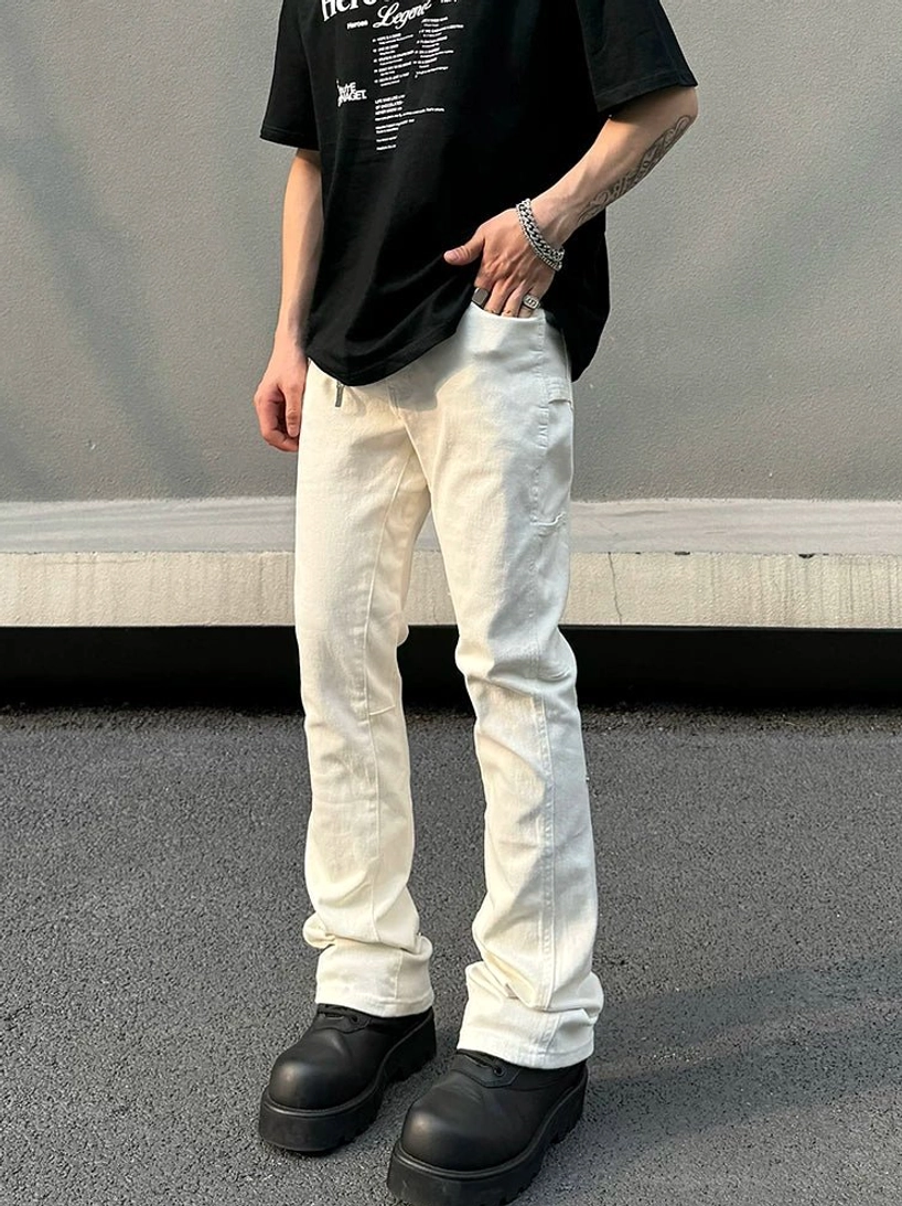 Side-front view of men's off-white utility flare jeans showing thigh pocket, metal hem snaps, black t-shirt, and platform boots