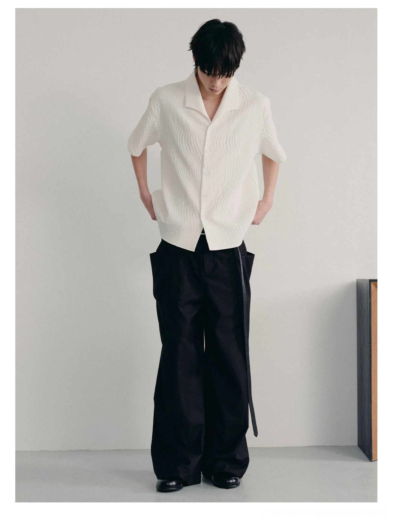Side back view of off-white textured quilted shirt paired with wide black trousers in minimalist streetwear styling
