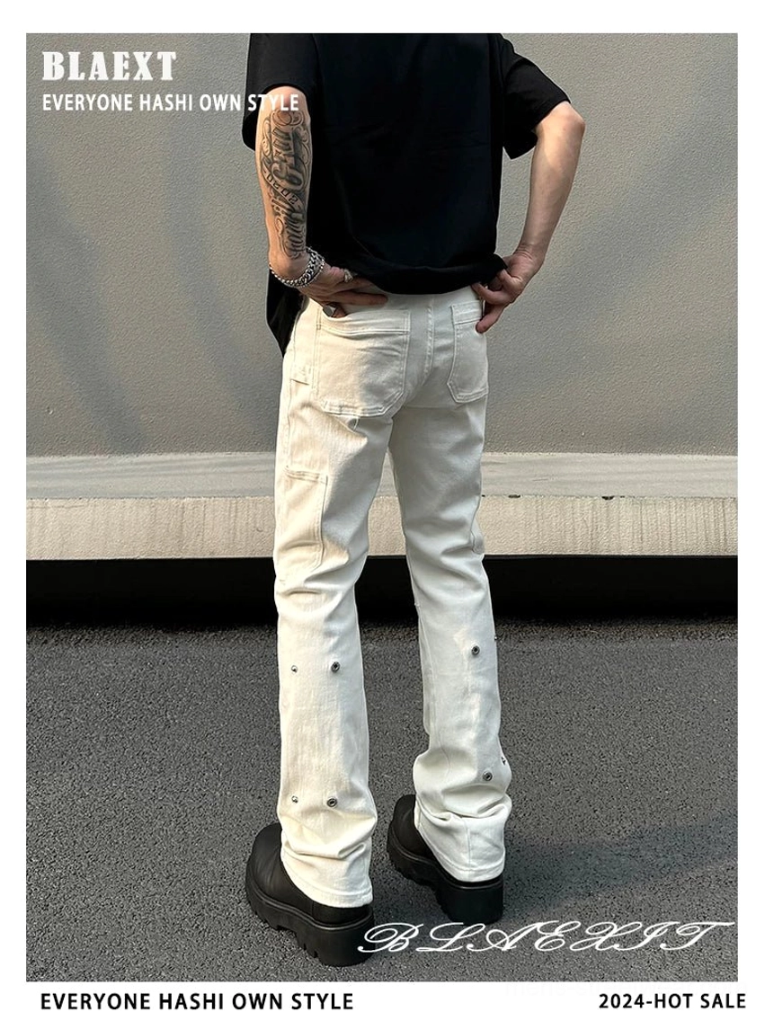 Back view of off-white utility flare streetwear jeans for men showing flared hems, rear pockets, and industrial snap-stud accents