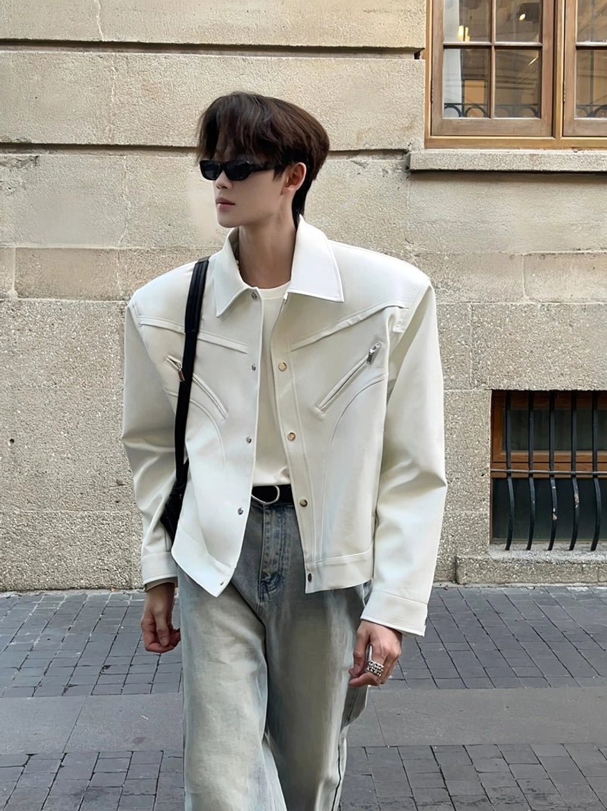 Off-white wide-shoulder cropped denim jacket shown from the right front side with classic collar, button placket, light wash jeans, and crossbody bag