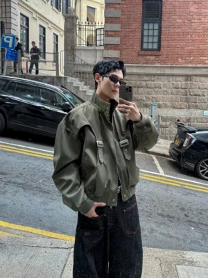 Olive buckle arc bomber jacket front selfie view styled with black wide leg jeans on a retro Hong Kong street