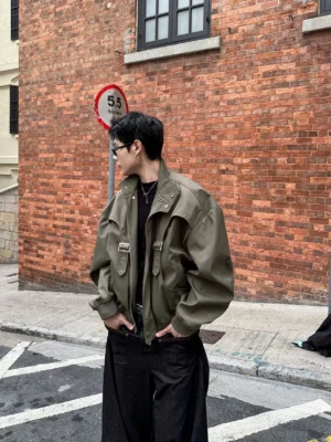Military green deconstructed utility bomber jacket side view showing dropped shoulders stand collar and metal buckle details