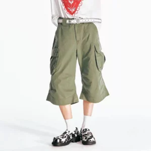 Front view of olive green flared utility cargo Bermuda shorts with oversized thigh pockets, wide cropped legs, white graphic T-shirt, belt, crew socks, and platform loafers
