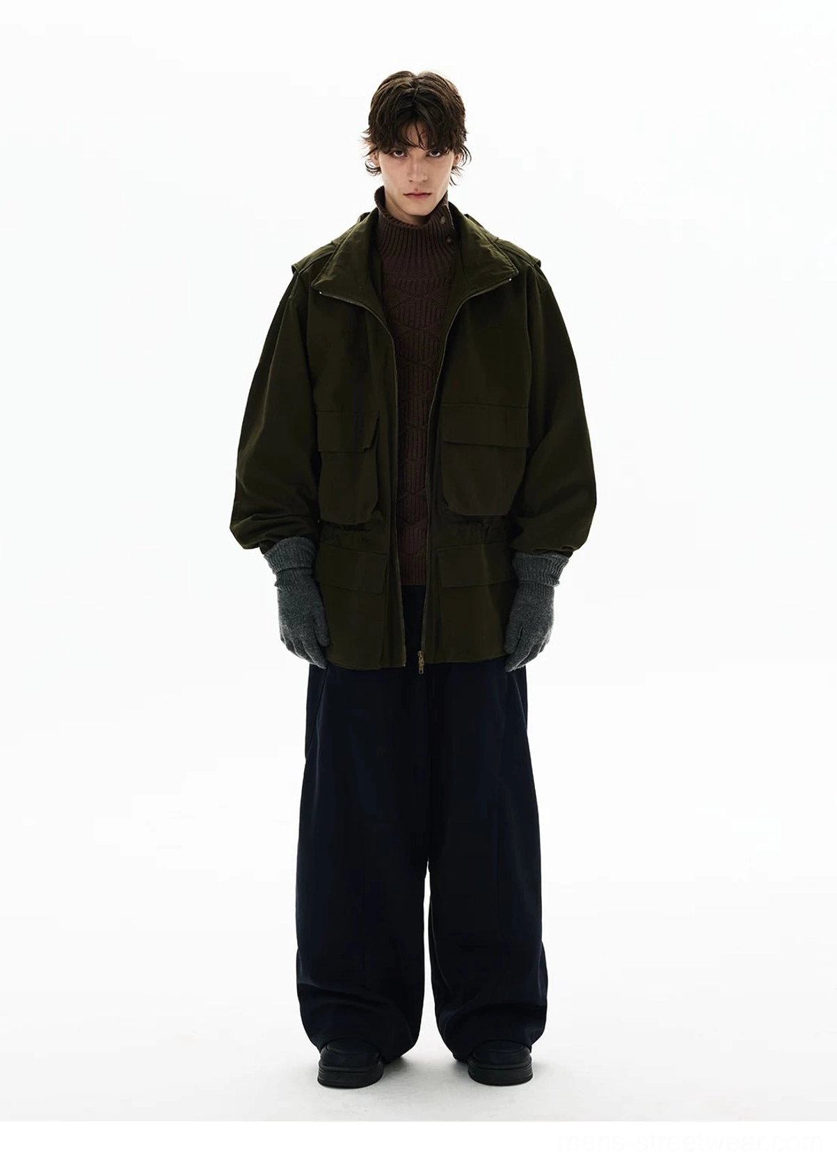 Olive green high collar utility parka styled over dark knitwear with relaxed tailoring and modern military-inspired streetwear details