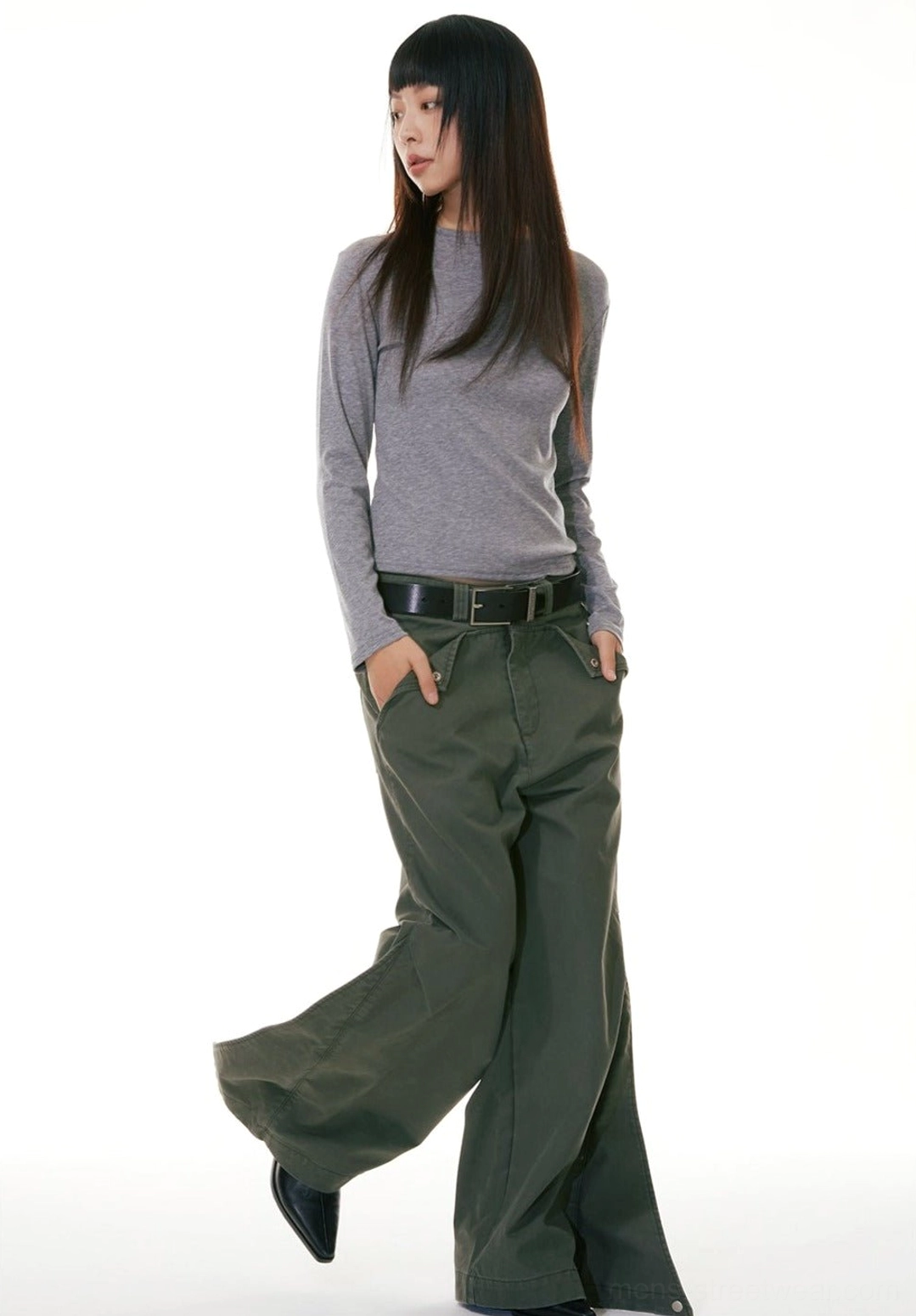 Three-quarter walking view of olive green wide-leg workwear denim jeans styled with a slim gray long-sleeve top and leather belt