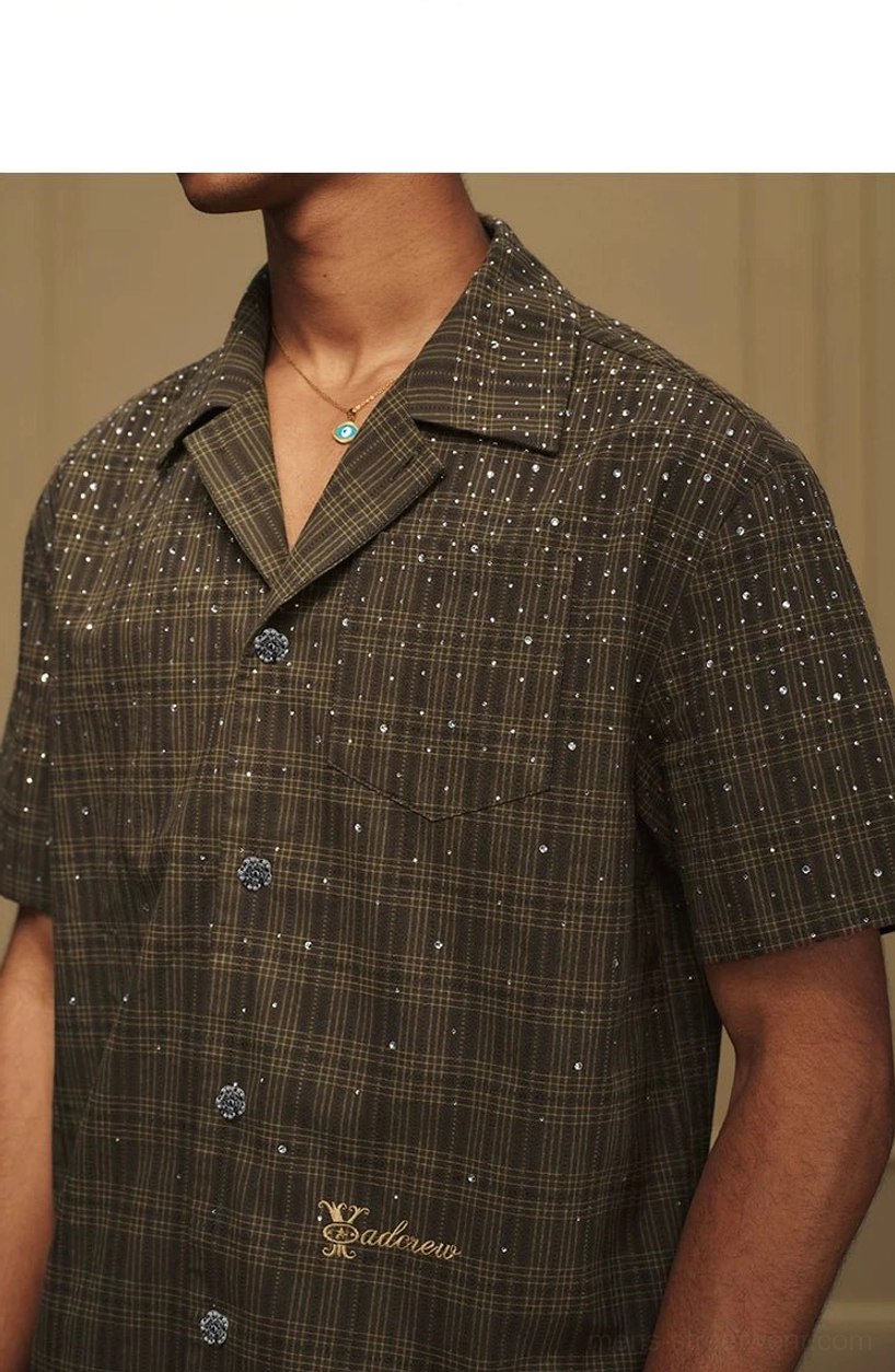 Close front detail of an olive plaid camp collar shirt showing sparkling embellishments, button placket, and chest pocket