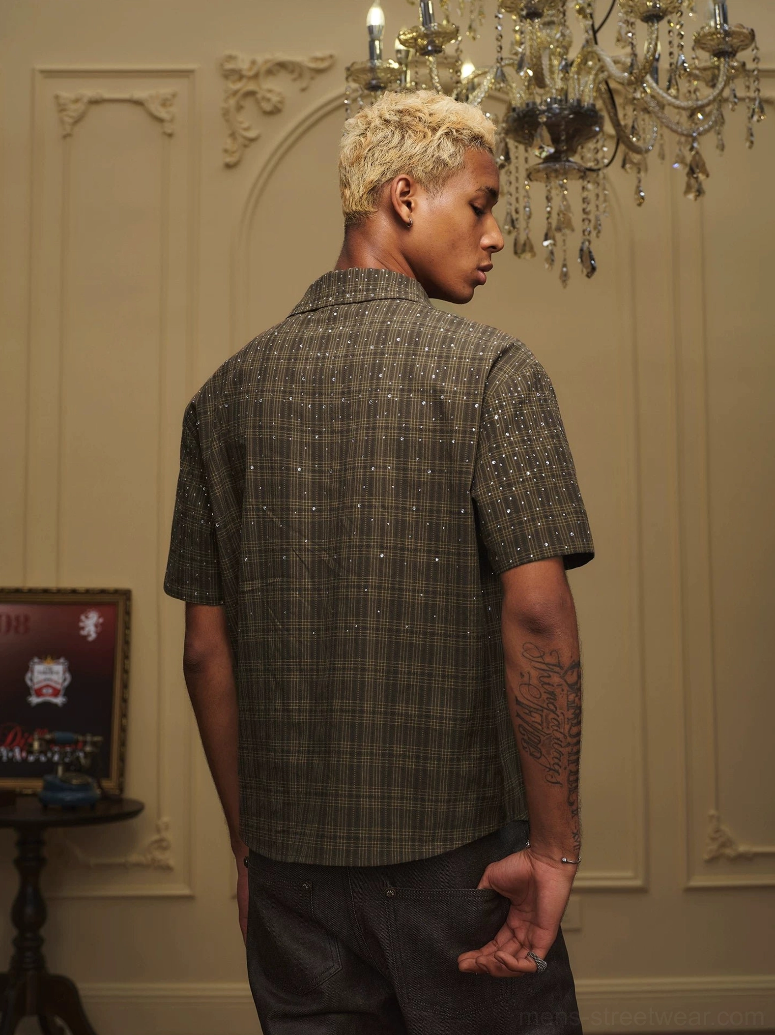 Rear view of an olive plaid rhinestone camp collar shirt with short sleeves and sparkling embellishments on a male model