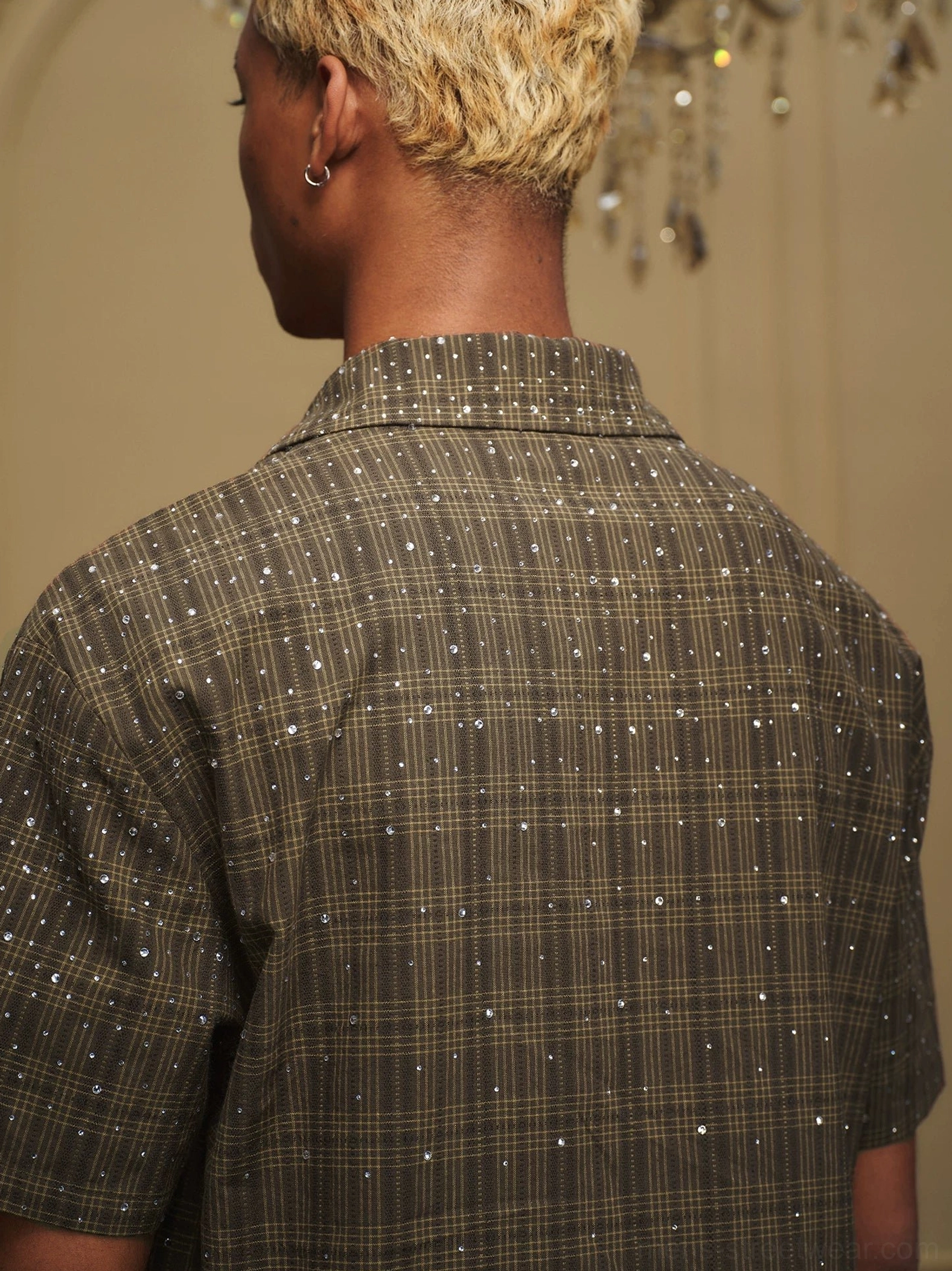 Close rear detail of textured olive plaid fabric with scattered sparkling embellishments on a camp collar shirt