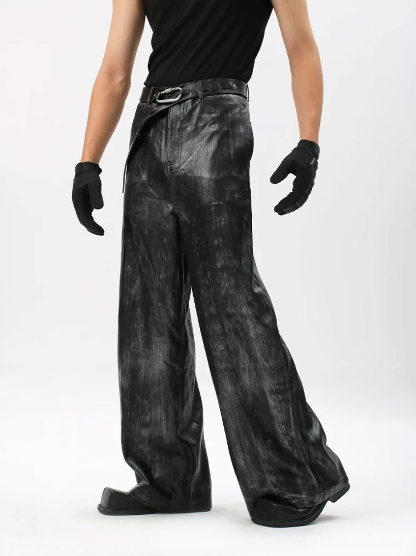 Front three-quarter view of black Onyx Mirage distressed wide-leg trousers with coated brushed texture and metal buckle belt styling