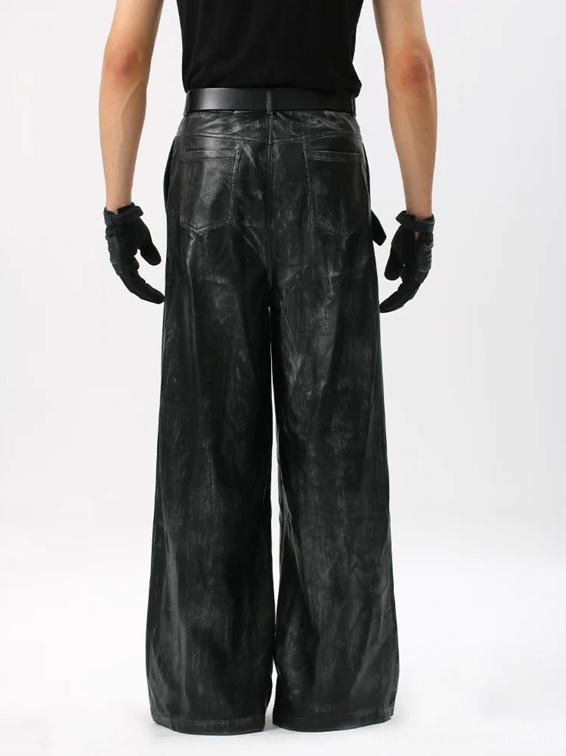 Rear view of black distressed coated wide-leg streetwear trousers with high waist, rear patch pockets, and marbled brushed finish