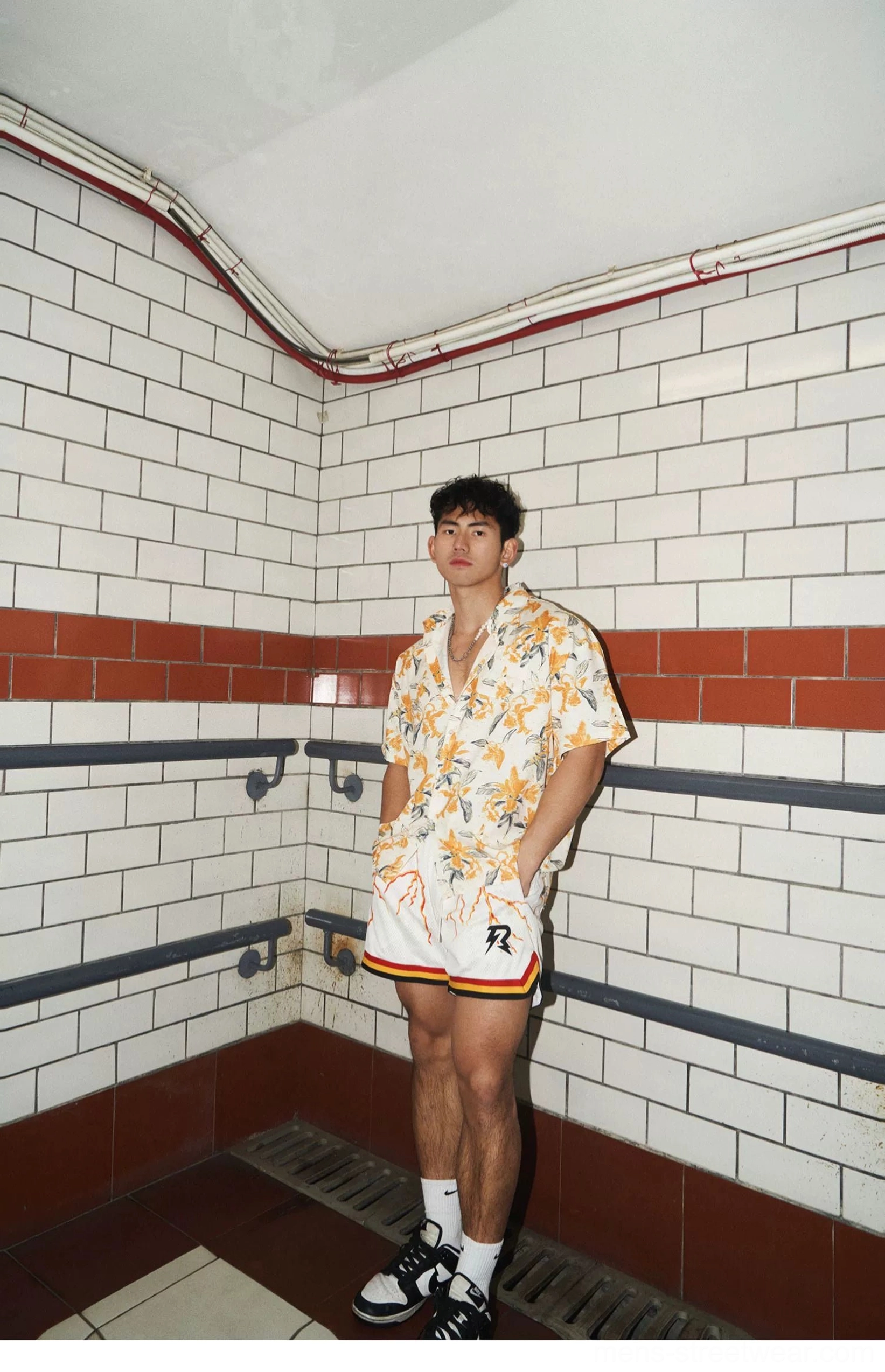 Full-body corner view of an orange and cream tropical floral shirt paired with relaxed white athletic shorts
