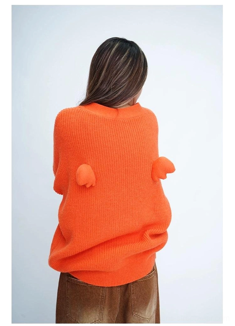 Full back view of a bright orange oversized fuzzy cardigan featuring twin wing-shaped pom-pom decorations and ribbed knit texture