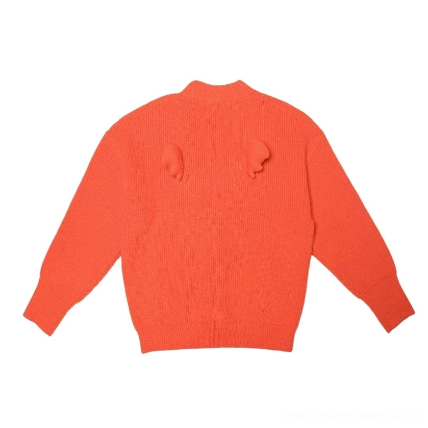 Orange oversized fuzzy knit cardigan with long sleeves, relaxed streetwear fit, button front, and playful wing pom-pom decoration