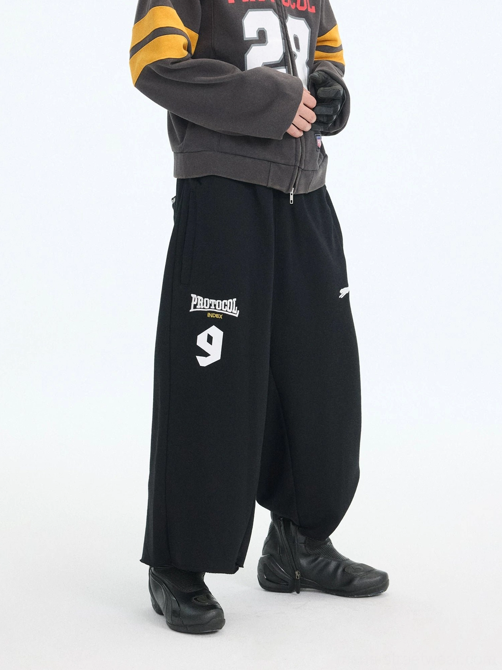 Black oversized 7/8 court shorts with dropped crotch, wide-leg cotton fleece silhouette, elasticated waistband, and varsity-style PROTOCOL 9 streetwear graphic
