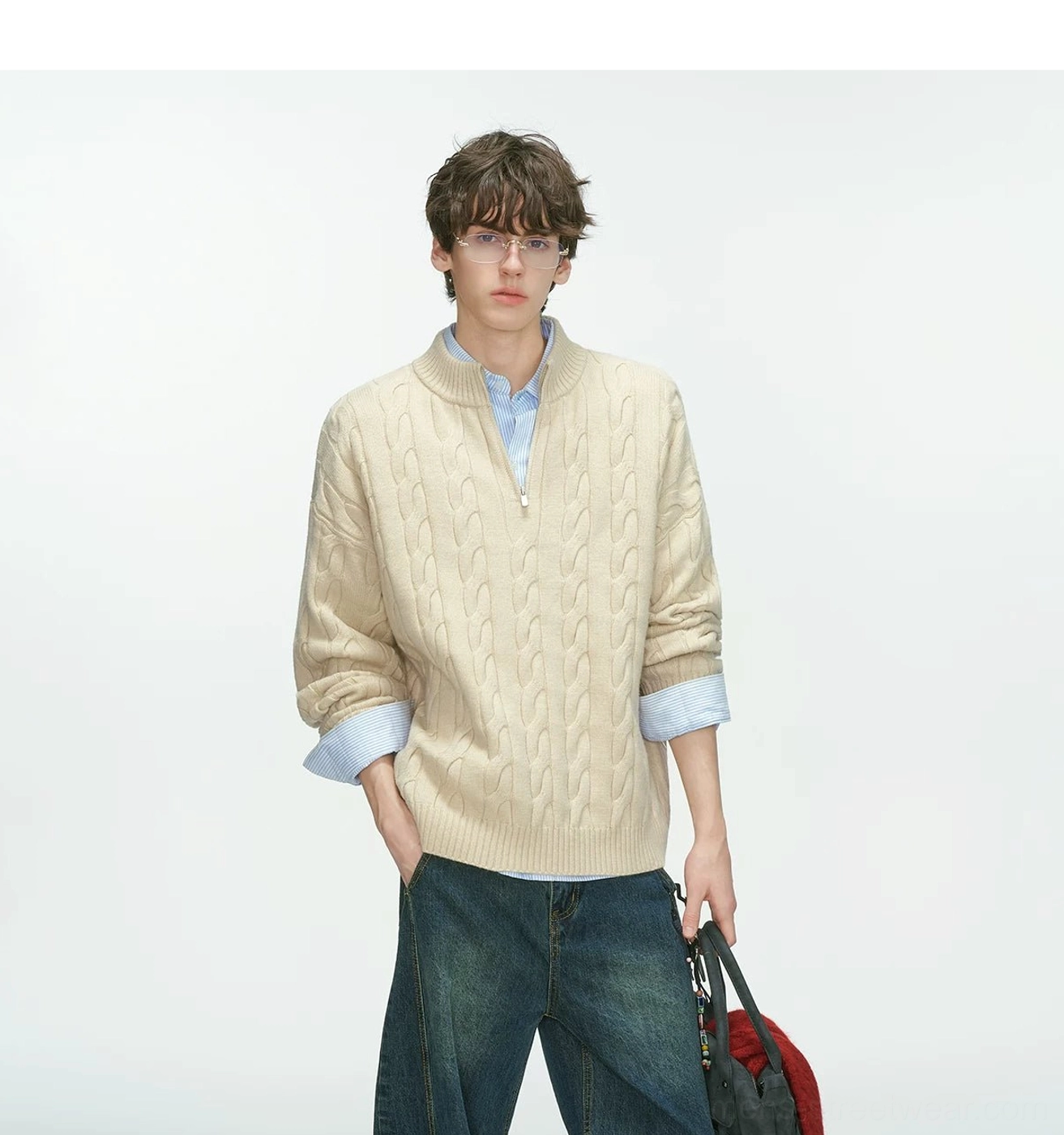 Front view of an oversized beige cable knit half-zip sweater styled with a blue shirt and dark wide-leg jeans