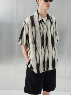 Rear three quarter view of oversized black beige tie dye short sleeve button up resort shirt with curved hem