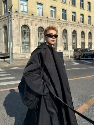 Front three quarter view of an oversized black belted padded overcoat with ankle length cut wide lapels and dropped shoulders styled as Seoul streetwear