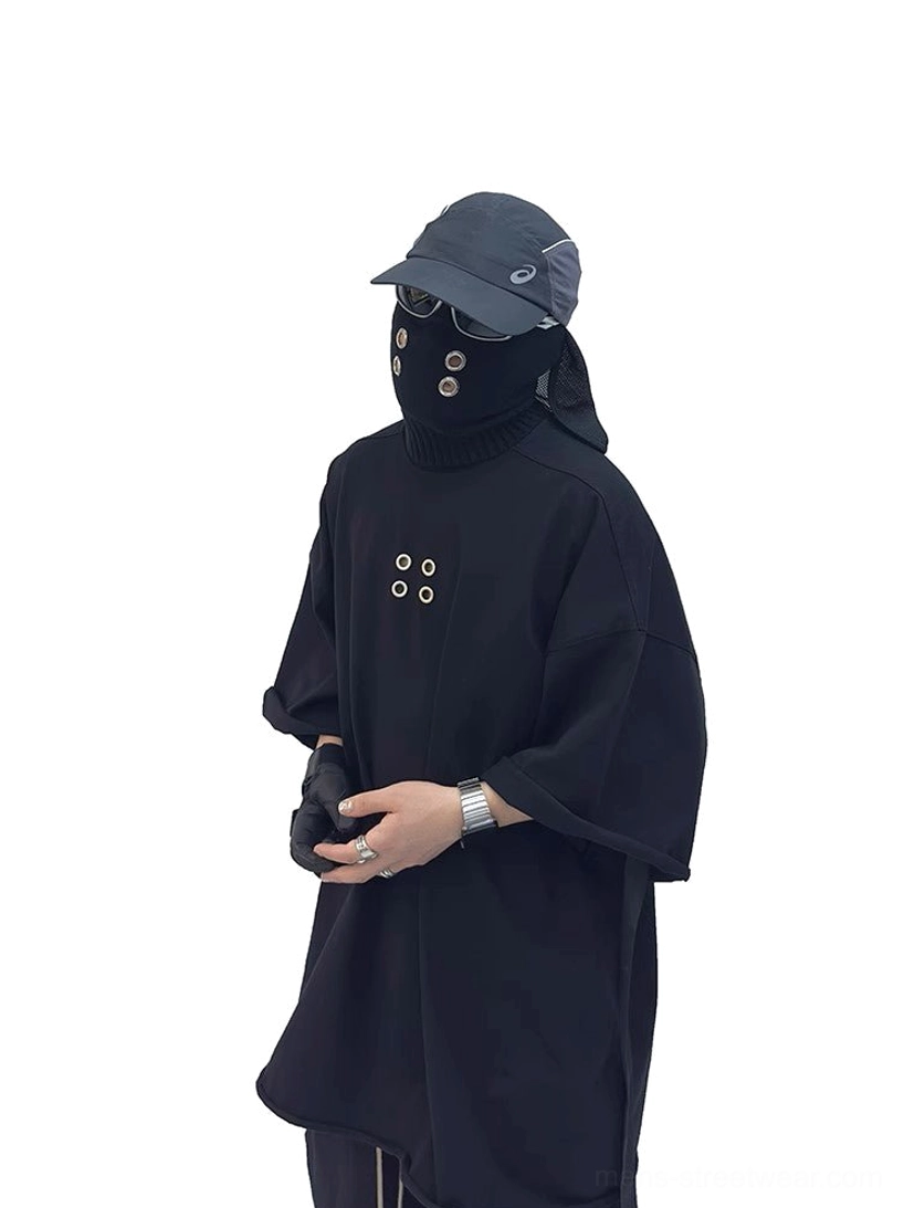 Oversized black cotton tee close view showing industrial metal eyelet chest design and relaxed wide silhouette