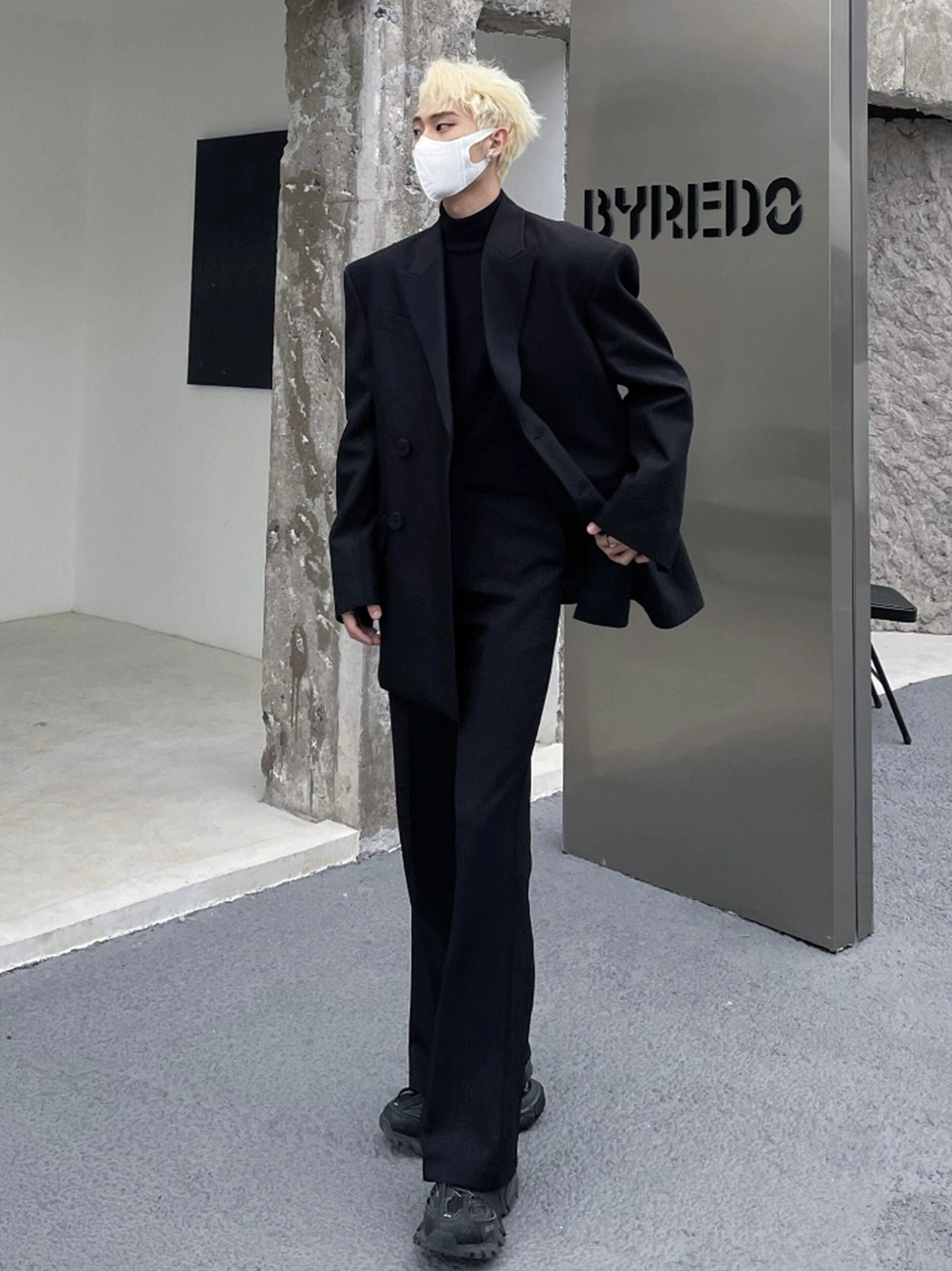 Side view of an oversized black double-breasted blazer worn with straight-leg trousers and leather shoes